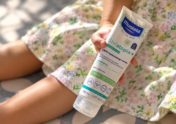 Child holding Mustela Stelatopia+ Lipid-Replenishing Cream for dry, eczema-prone skin